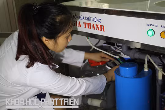 TS Nguyễn Thị Thanh Hải - đồng tác giả Giải pháp hữu ích - bên một thiết bị sản xuất anolit thường dùng trong bệnh viện, trạm y tế, trường học. Ảnh: Phạm Phượng