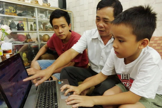Tám năm trôi qua, con trai lớn của thầy Ninh giờ đã học lớp 9 (bìa trái). Phần mềm học chữ, tính toán giờ đây được thầy Ninh hướng dẫn tiếp cho con trai đang học tiểu học của mình - Ảnh: NHƯ HÙNG
