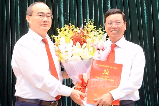 Bí thư Thành ủy TPHCM Nguyễn Thiện Nhân trao quyết định và hoa chúc mừng ông Vũ Ngọc Tuất.