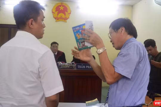 Họa sĩ Lê Linh (áo trắng) và ông Nguyễn Vân Nam (người đang cầm cuốn sách) - đại diện cho công ty Phan Thị với những trao đổi gay gắt tại tòa 