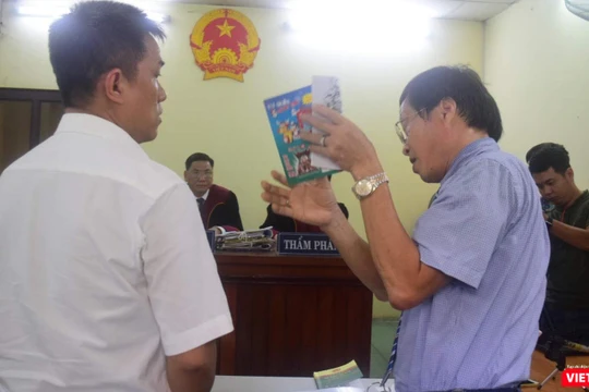 Họa sĩ Lê Linh (áo trắng) và ông Nguyễn Vân Nam (người đang cầm cuốn sách) - đại diện cho công ty Phan Thị với những trao đổi gay gắt tại tòa 