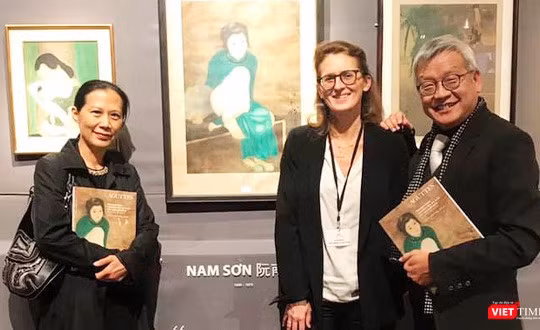 Nhà nghiên cứu Ngô Kim Khôi (bên phải) cạnh bức tranh lụa "Thiếu nữ cầm quạt" của họa sĩ Nam Sơn trưng bày tại Pháp 