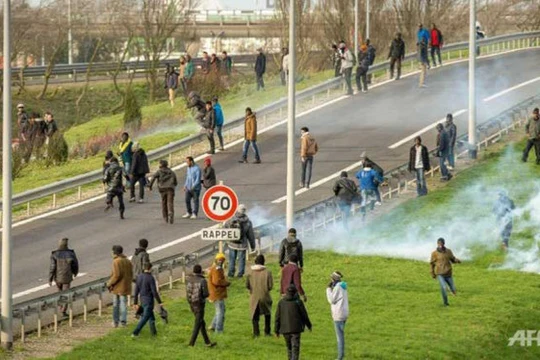 Cảnh sát Pháp dùng hơi cay giải tán đám đông những người di cư cố vào đường hầm để qua Anh - Ảnh: AFP