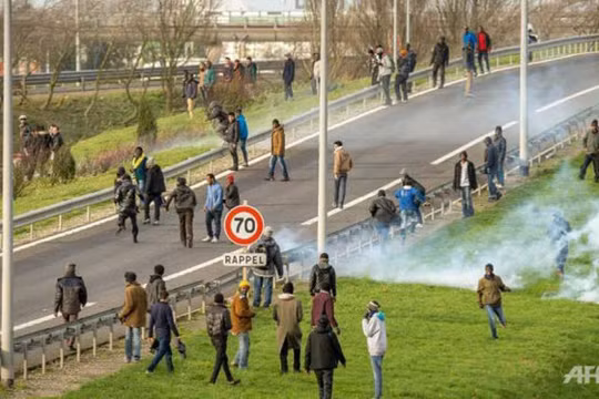 Cảnh sát Pháp dùng hơi cay giải tán đám đông những người di cư cố vào đường hầm để qua Anh - Ảnh: AFP