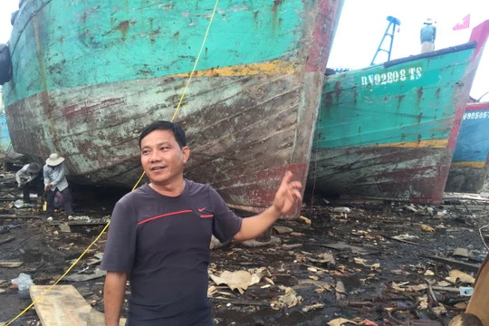 Ông Trà Văn Hoành bên tàu gỗ cỡ lớn đang bảo trì, sửa chữa định kỳ - Ảnh: MINH ĐỨC