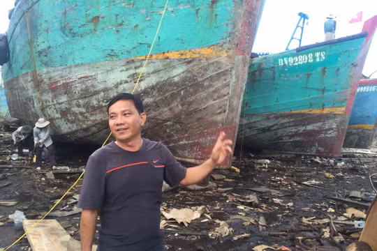 Ông Trà Văn Hoành bên tàu gỗ cỡ lớn đang bảo trì, sửa chữa định kỳ - Ảnh: MINH ĐỨC
