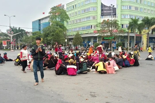 Người dân Sầm Sơn ngồi la liệt dưới lòng đường ngã tư đại lộ Lê Lợi - Trần Phú. Ảnh: Nguyễn Dương.