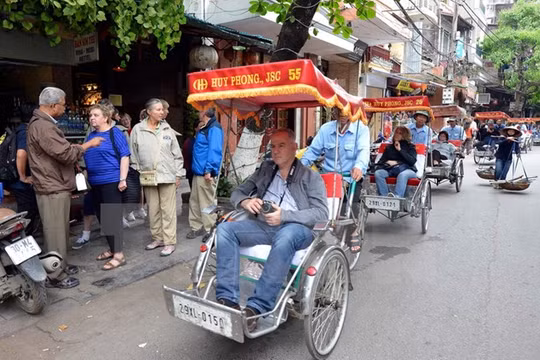 Du khách nước ngoài thăm phố cổ Hà Nội bằng xe xích lô. (Ảnh: Thanh Hà/TTXVN)