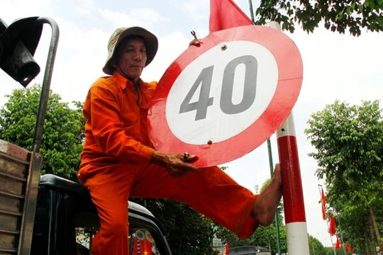 Công nhân Công ty Công trình Đô thị Bình Dương tháo dỡ biển hạn chế tốc độ 40km/h tại đường Thích Quảng Đức, TP Thủ Dầu Một chiều 28/1. 