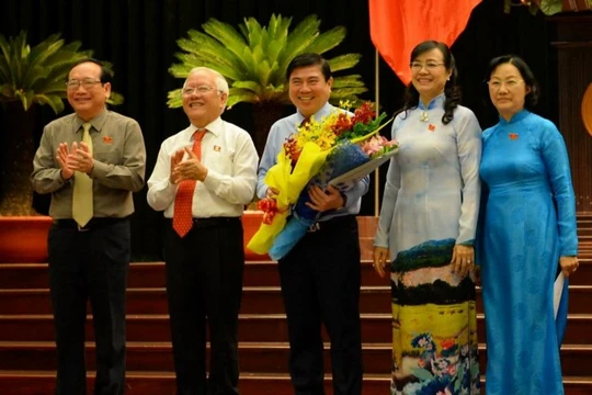 Chủ tịch UBND TP.HCM Nguyễn Thành Phong (giữa) nhận hoa chúc mừng từ ông Lê Hoàng Quân và bà Nguyễn Thị Quyết Tâm - Ảnh: Diệp Đức Minh