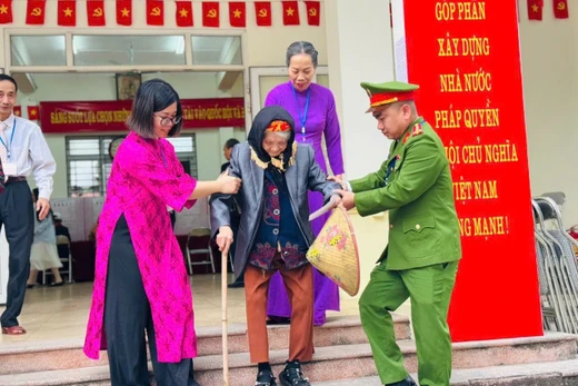 Cán bộ tổ bầu cử ở Hà Nội giúp cụ bà di chuyển sau khi bỏ phiếu. 