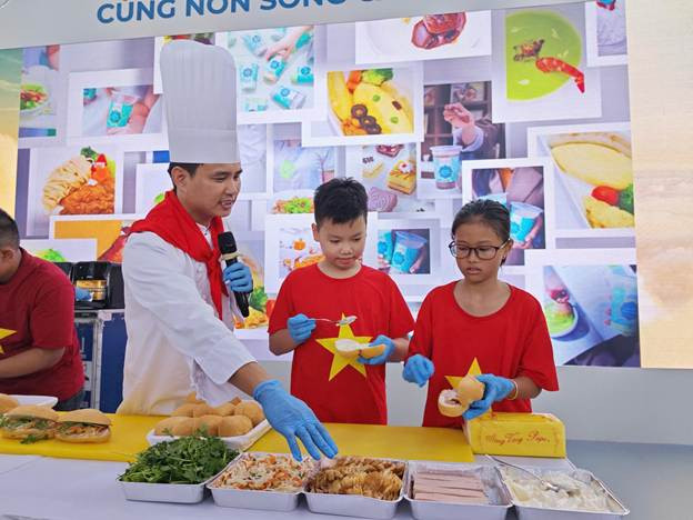 Em nhỏ say sưa tạo hình chiếc bánh mỳ đầu tiên của mình. (Ảnh: VNA).