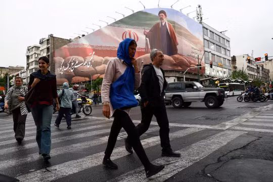 Người dân đi bộ gần một bảng quảng cáo có hình ảnh nhà lãnh đạo tối cao mới của Iran, Mojtaba Khamenei, trong bối cảnh thỏa thuận ngừng bắn giữa Mỹ và Iran, tại Tehran, Iran ngày 20/4. Ảnh: Reuters.