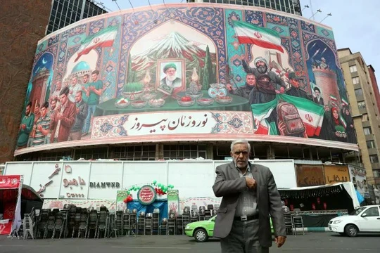 Người dân Iran đi ngang qua một bảng quảng cáo tại quảng trường Valiasr ở Tehran, Iran ngày 22/3. Ảnh: EPA.