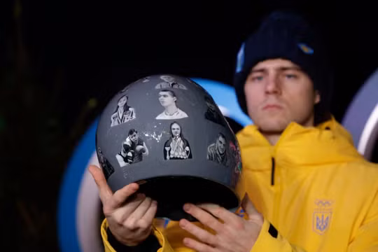 Vận động viên Vladyslav Heraskevych của Ukraine giơ cao chiếc mũ bảo hiểm đặc biệt tại một cuộc họp báo. Ảnh: Reuters.