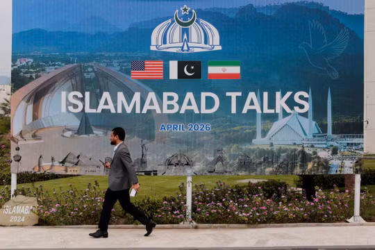 Một người đàn ông đi ngang qua bảng quảng cáo gần trung tâm truyền thông khi các phái đoàn từ Mỹ và Iran dự kiến ​​sẽ tổ chức đàm phán hòa bình tại Islamabad, Pakistan ngày 11/4. Ảnh: Reuters.