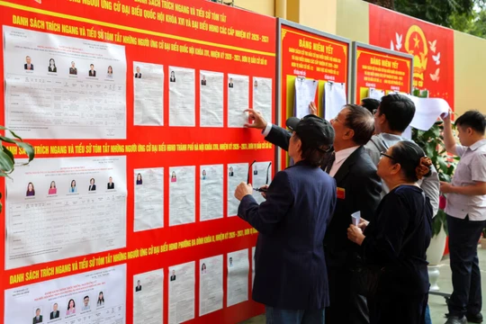 Người dân xem bảng thông tin về các ứng cử viên bên ngoài một điểm bỏ phiếu trong cuộc bầu cử Quốc hội, tại Hà Nội ngày 15/3. Ảnh: Reuters.