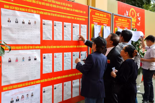 Người dân xem bảng thông tin về các ứng cử viên bên ngoài một điểm bỏ phiếu trong cuộc bầu cử Quốc hội, tại Hà Nội ngày 15/3. Ảnh: Reuters.