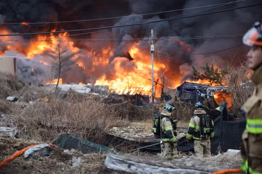 Ngày 16/1, các nhân viên cứu hỏa hướng mắt về phía đám cháy đang bao trùm làng Guryong, khu ổ chuột cuối cùng ở quận Gangnam, Seoul, Hàn Quốc. Ảnh: Reuters.