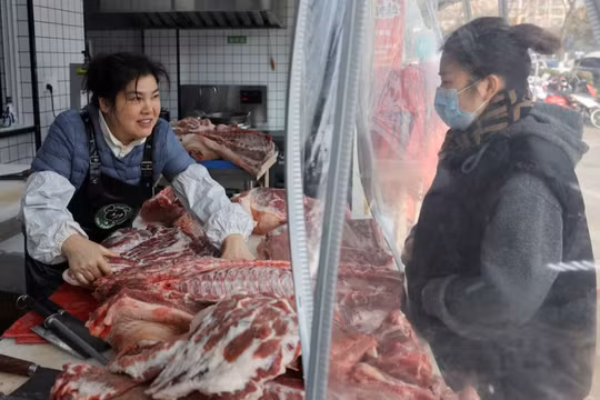 Nhân viên phục vụ khách hàng mua thịt lợn tại một cửa hàng thịt lợn đen ở Thái Châu, tỉnh Giang Tô, Trung Quốc, ngày 16/1. Ảnh: Reuters.