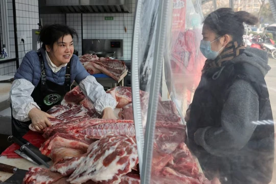 Nhân viên phục vụ khách hàng mua thịt lợn tại một cửa hàng thịt lợn đen ở Thái Châu, tỉnh Giang Tô, Trung Quốc, ngày 16/1. Ảnh: Reuters.