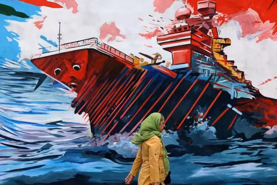 Một người phụ nữ đi ngang qua bức tranh tường phản đối lực lượng Mỹ và Israel ở Tehran, Iran ngày 8/4. Ảnh: AFP.