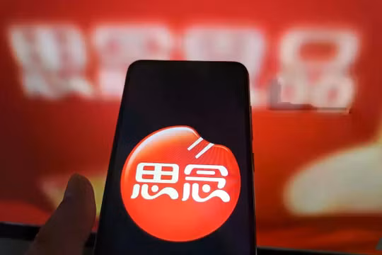 Một người dùng Internet đang xem trang web của Synear Food trên máy tính của mình, trong khi logo của công ty hiển thị trên điện thoại. Công ty này đã bị Washington đưa vào danh sách đen vì bị cáo buộc sử dụng lao động cưỡng bức. Ảnh: Getty.