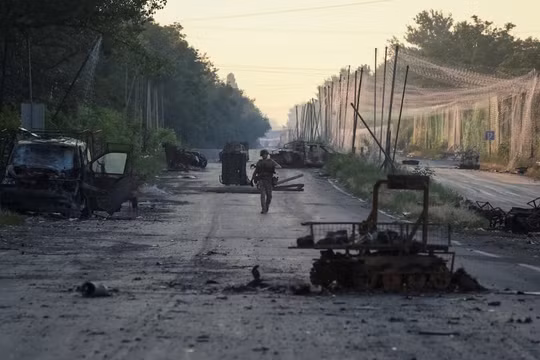 Một binh sĩ thuộc Lữ đoàn hợp nhất "Khyzhak" của Cảnh sát tuần tra Ukraine đi dọc theo một con đường gần lưới chống UAV và các phương tiện quân sự bị phá hủy khi tham gia nhiệm vụ bảo vệ một con đường khỏi UAV của Nga giữa các thị trấn tiền tuyến Druzhkivka và Kostiantynivka, ngày 24/6. Ảnh: Reuters.
