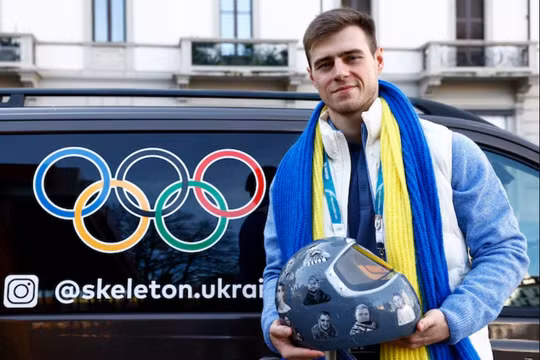 Vận động viên Ukraine Vladyslav Heraskevych chụp ảnh cùng chiếc mũ bảo hiểm sau khi bị truất quyền thi đấu. Ảnh: Reuters.