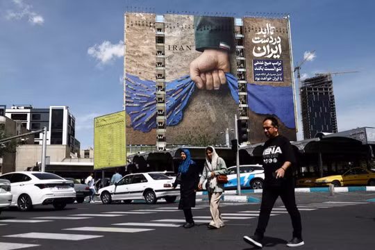 Người dân đi ngang qua một bảng quảng cáo có hình ảnh về eo biển Hormuz trên một tòa nhà ở Tehran, Iran ngày 27/4. Ảnh: Reuters.