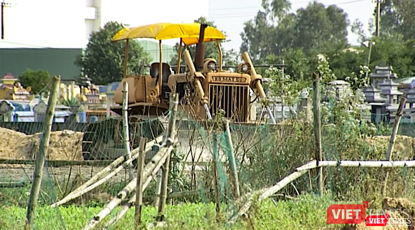 Máy móc xen lẫn ruộng hoa màu và nghĩa địa của người dân địa phương