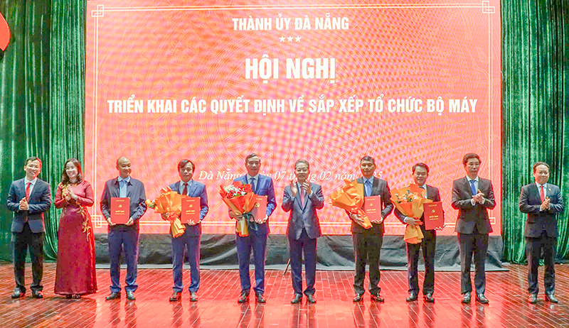 Ông Nguyễn Văn Quảng (thứ 5 từ phải sang), Bí thư Thành ủy Đà Nẵng trao quyết định cho ông Lê Trung Chinh (thứ 5 từ trái sang) và các cá nhân tại hội nghị.