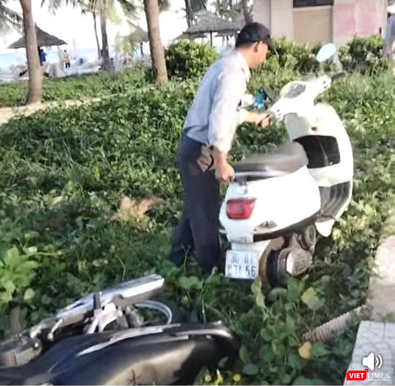 Hình ảnh nhân viên trật tự Ban quản lý bán đảo Sơn Trà và các bãi biển du lịch Đà Nẵng cố gắng di chuyển xe máy để sai quy định, ảnh hưởng lối đi bộ của du khách.