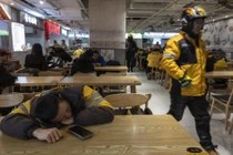Một nhân viên giao hàng ở Trung Quốc tranh thủ nghỉ ngơi sau giờ cao điểm ăn trưa. Ảnh: WSJ.