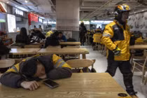 Một nhân viên giao hàng ở Trung Quốc tranh thủ nghỉ ngơi sau giờ cao điểm ăn trưa. Ảnh: WSJ.