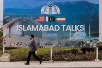 Một người đàn ông đi ngang qua bảng quảng cáo gần trung tâm truyền thông khi các phái đoàn từ Mỹ và Iran dự kiến ​​sẽ tổ chức đàm phán hòa bình tại Islamabad, Pakistan ngày 11/4. Ảnh: Reuters.