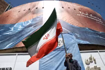 Một người đàn ông cầm cờ Iran gần một bảng quảng cáo chống Mỹ có hình Tổng thống Mỹ Donald Trump và eo biển Hormuz, tại Tehran, Iran, ngày 30/5. Ảnh: Reuters.