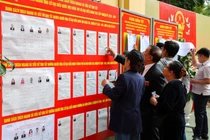 Người dân xem bảng thông tin về các ứng cử viên bên ngoài một điểm bỏ phiếu trong cuộc bầu cử Quốc hội, tại Hà Nội ngày 15/3. Ảnh: Reuters.