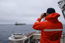 Một sĩ quan thuộc Lực lượng Bảo vệ bờ biển Mỹ đang quan sát qua ống nhòm tàu ​​chở dầu Bella 1 có liên hệ với Nga, vốn đã được đổi tên thành Marinera. Ảnh: Reuters.