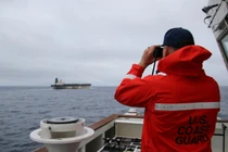 Một sĩ quan thuộc Lực lượng Bảo vệ bờ biển Mỹ đang quan sát qua ống nhòm tàu ​​chở dầu Bella 1 có liên hệ với Nga, vốn đã được đổi tên thành Marinera. Ảnh: Reuters.