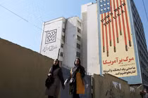 Hai phụ nữ đi qua một biểu ngữ nội dung chống Mỹ ở Tehran, Iran. Ảnh: Getty.