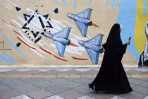 Một người phụ nữ đi bộ bên cạnh một bức tranh tường chống Israel trên đường phố, trong bối cảnh lệnh ngừng bắn giữa Mỹ và Iran, tại Tehran, Iran ngày 20/4. Ảnh: Reuters.