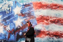 Một phụ nữ Iran đi ngang qua một bảng quảng cáo chống Mỹ ở Tehran, Iran ngày 26/2. Ảnh: Reuters.