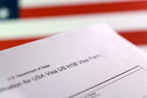 Một lá cờ Mỹ và một mẫu đơn xin thị thực H-1B. Ảnh minh họa: Reuters.
