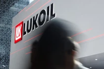 Một người đi ngang qua logo của Lukoil trong sự kiện thường niên Triển lãm và Hội nghị Dầu khí Quốc tế Abu Dhabi (ADIPEC) tại Abu Dhabi, UAE ngày 3/11/2025. Ảnh: Reuters.