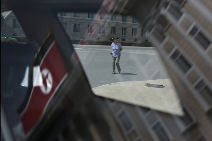 Hình ảnh cờ của Triều Tiên phấp phới bay in trên kính chắn gió của một chiếc xe ôtô đậu ngay quảng trường Kim Nhật Thành ở Bình Nhưỡng.