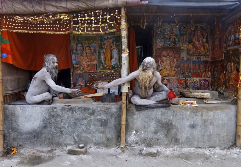 Naga Sadhus, người thánh Hindu chia nhau điếu thuốc trong trại tạm gần nơi hợp lưu của sông Hằng và vịnh Bengal, trước lễ hội 