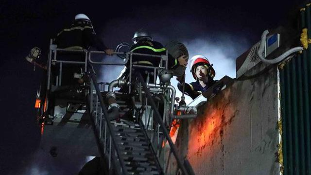 Vài giờ sau khi đám cháy được kiểm soát, lực lượng cảnh sát PCCC&amp;CNCH vẫn tiếp tục sử dụng thang cứu hộ xử lý đám cháy. Ảnh: TTXVN.