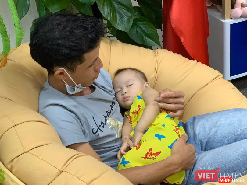 Em bé vừa tròn tuổi, mạnh khỏe, ngủ ngoan trong vòng tay bố.
