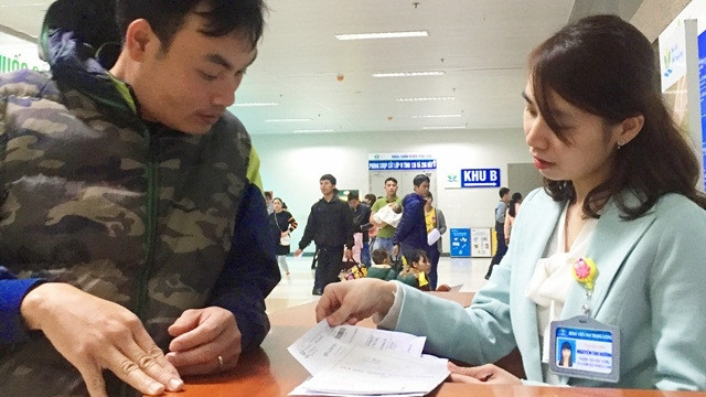 Một phụ huynh được nhân viên của Bệnh viện Nhi Trung ương hướng dẫn thủ tục thanh toán ra viện.